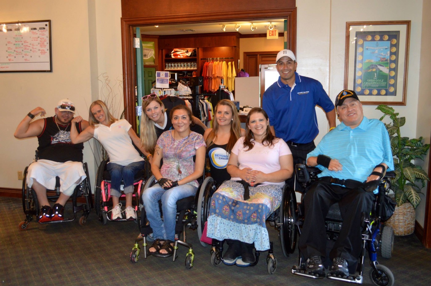 Members in wheelchairs, staff and volunteers smiling together at the golf tournament.